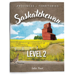 A printed workbook cover titled "Saskatchewan" with "Provinces + Territories" at the top and "Level 2" near the bottom. The artwork shows a rural Saskatchewan landscape with a red-brown grain elevator, yellow field, blue sky, white clouds, and a dirt road.